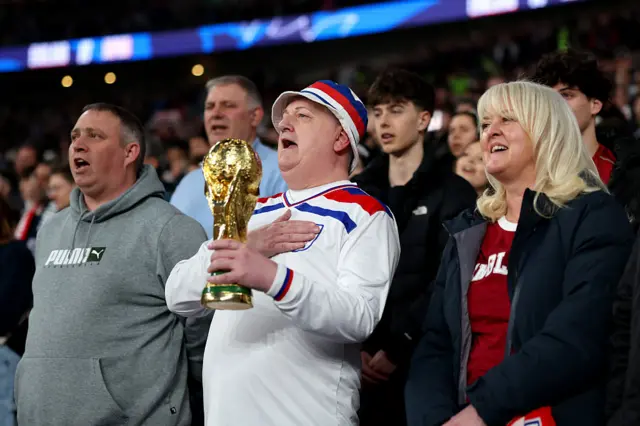 An England fan holds a replica of the FIFA World Cup Trophy as they stand for the national anthem prior to the international friendly match between England and Japan at Wembley Stadium on March 31, 2026 in London, England.