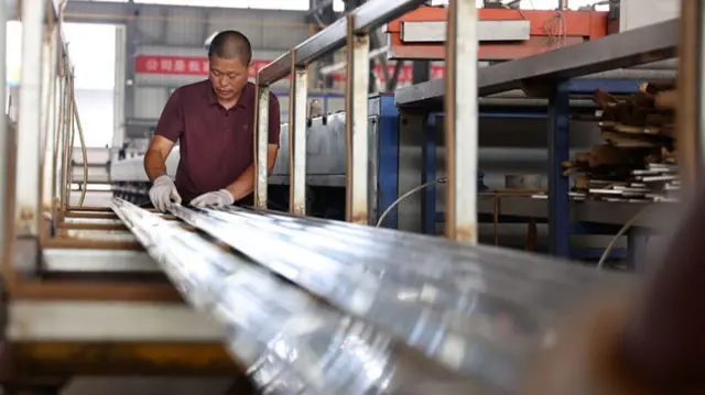 A worker handles aluminium columns at a factory in China