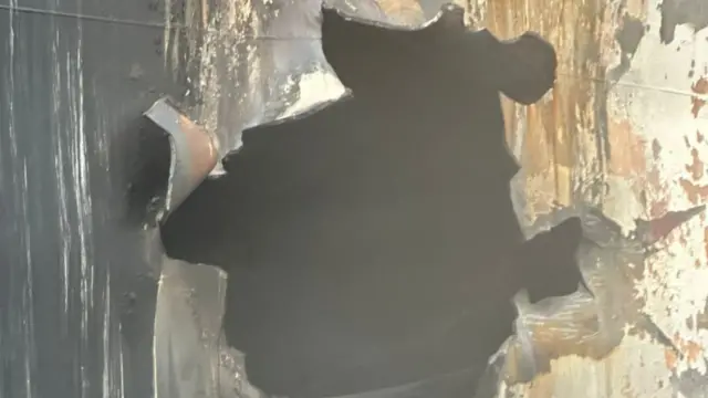 A large hole in the metal hull of the ship that was reportedly attacked