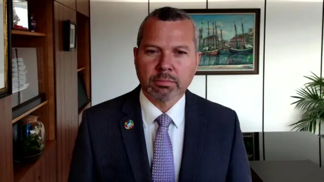 Arsenio Dominguez wearing a suit over a white shirt and purple tie.