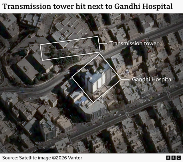 A satellite image showing a collapsed transmission tower behind a large hospital building