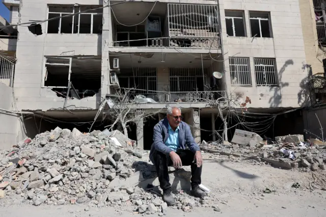 An Iranian man sits next to the damaged remains of his residential building in central Tehran, Iran, 04 March 2026