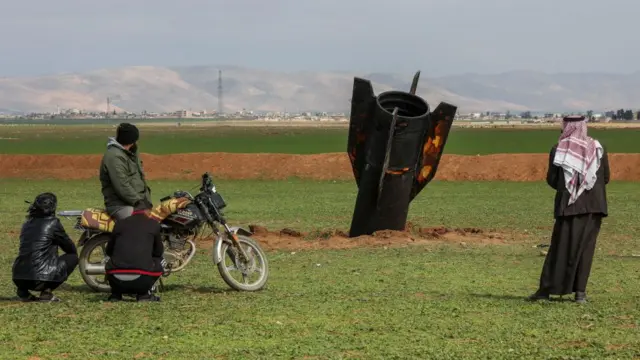 People stand next to an Iranian missile after it fell near Qamishli International Airport, Syria