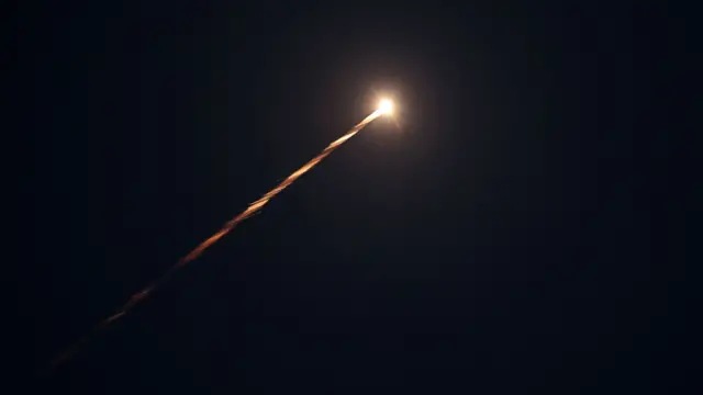 A bright fireball with a tail shaped like a comet's is seen streaking in the night sky