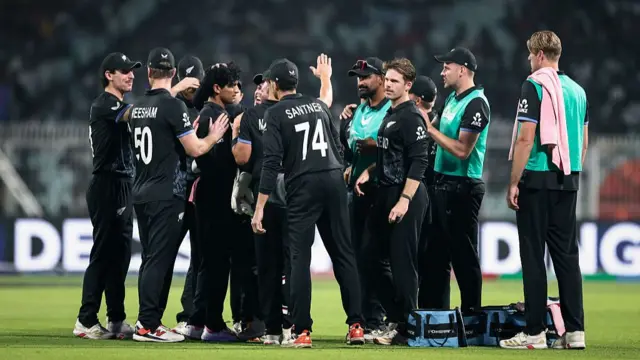 : Rachin Ravindra of New Zealand celebrates the wicket of Aiden Markram of South Africa with teammates