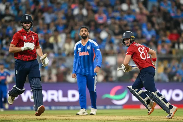 England's Will Jacks (L) and Jacob Bethell (R) run between the wickets as India's Varun Chakravarthy looks on