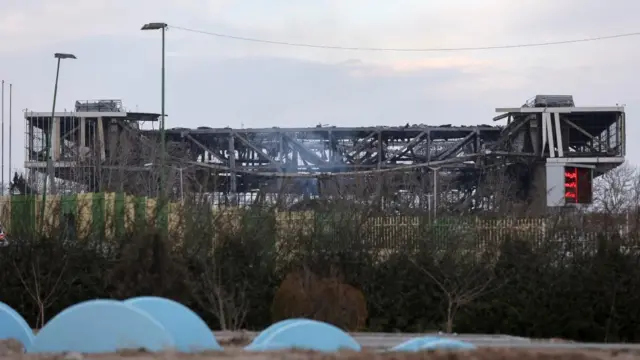 Smoke rises over the wreckage of the Azadi Stadium following an attack. The metal pillars holding up the structure have emerged following destruction