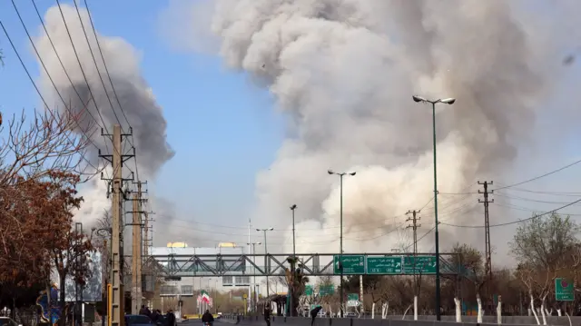 White and grey smoke rises over a motorway in Tehran as strikes on Iran continue