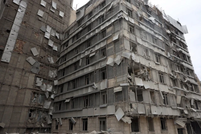 Exterior view on the damaged Gandhi hospital, several panels hanging off windows and the building is covered in dust