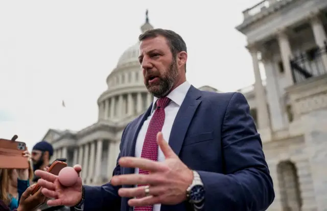 Senator Markwayne Mullin holds a rubber ball while speaking with journalists on the steps of the US Capitol