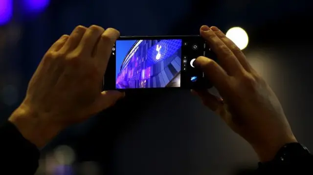 A fan is seen taking a photograph of the stadium from the outside