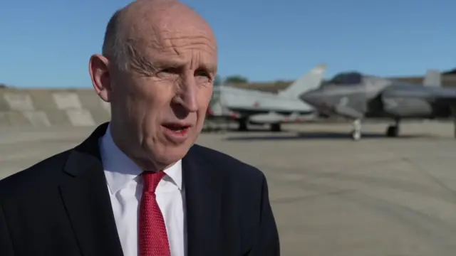 John Healey speaking while standing on airfield