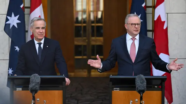 Mark Carney and Anthony Albanese wear suits speaking at microphones during a press conference