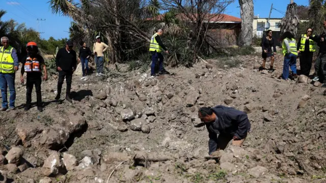 People stand around to look at the damage caused by missiles launched from Iran