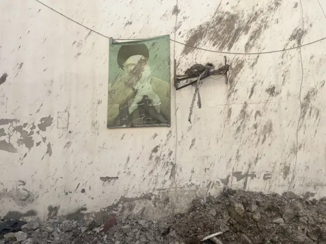 A scratched out poster of former Hezbollah leader Hassan Nasrallah hanging from a damaged wall