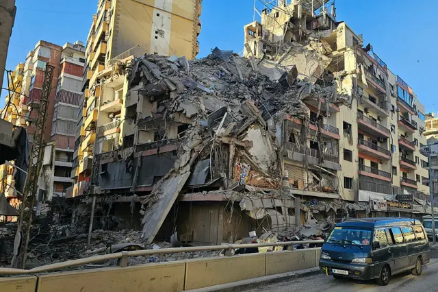 A van drives past a destroyed building following airstrikes in Beirut's southern suburbs of Ghobeiry neighborhood