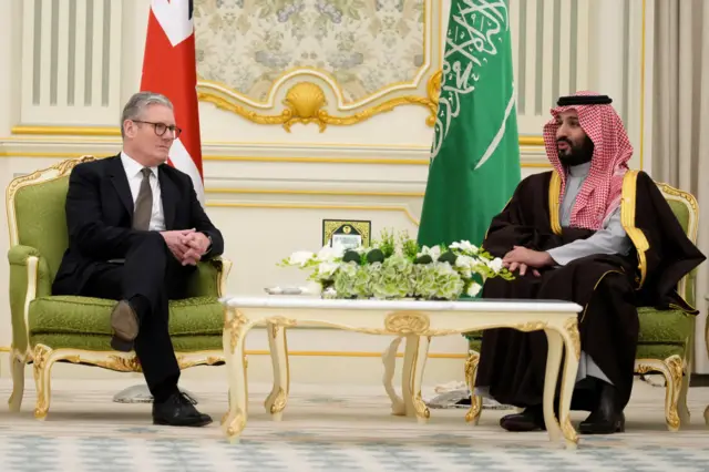 Keir Starmer and MBS sit in ornate chairs with a coffee table between them and their national flags behind them