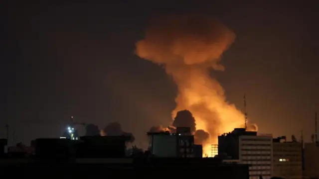 Smoke rises from an orange fire burning at night over some tower blocks