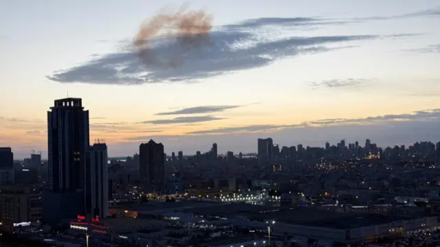 Smoke rises over a city skyline after an Iranian drone was intercepted in Manama, Bahrain