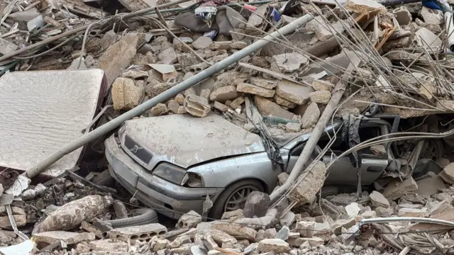 A car lies under rubble