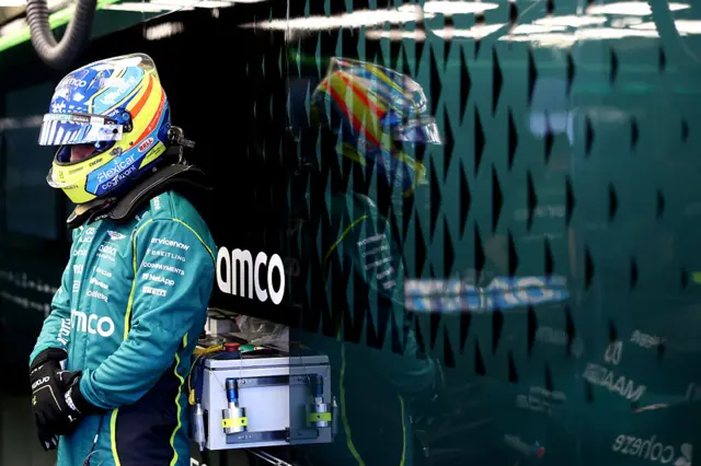 Fernando Alonso waits in the Aston Martin garage