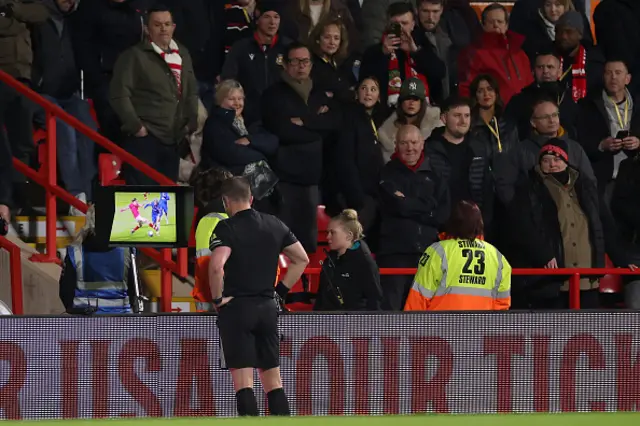 Referee Peter Bankes watches the pitch side VAR monitor