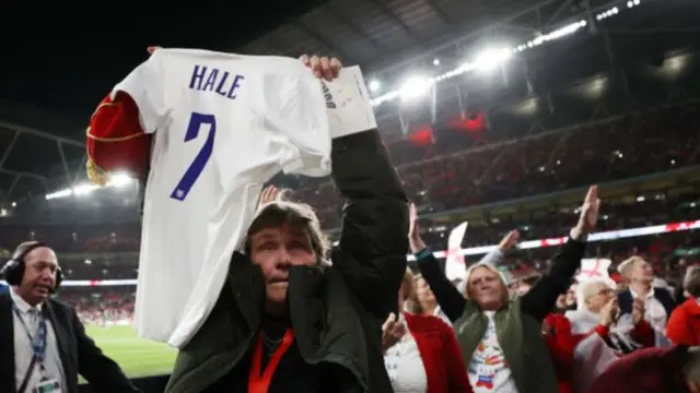 Lynda Hale holds up a shirt with her name on at Wembley