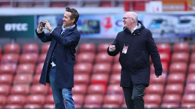 Ryan Reynolds takes a photo on the pitch at Wrexham