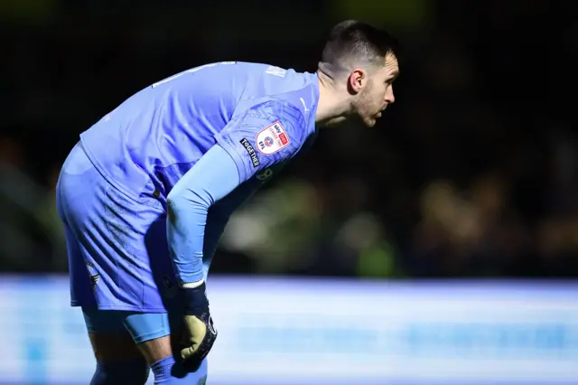 Oldham goalkeeper Mathew Hudson bending down while looking forwards