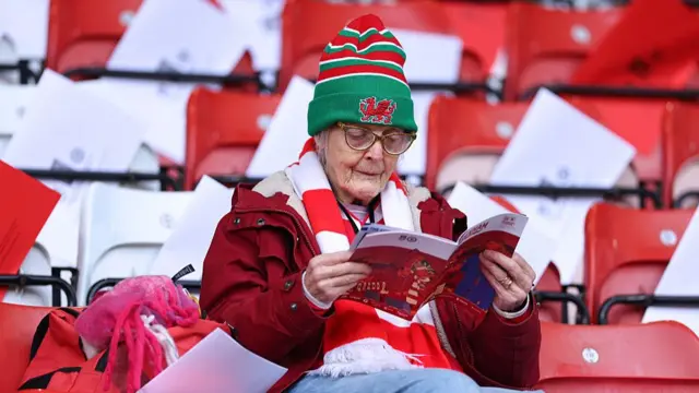 A Wrexham fan reads a programme