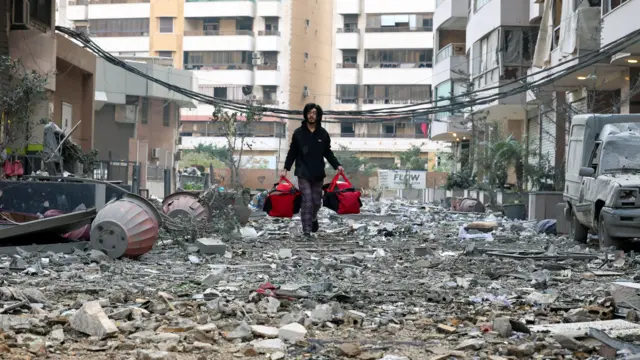 A man carries bags through rubble in Beirut