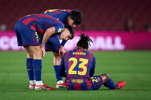 Jules Kounde of FC Barcelona lies injured on the pitch