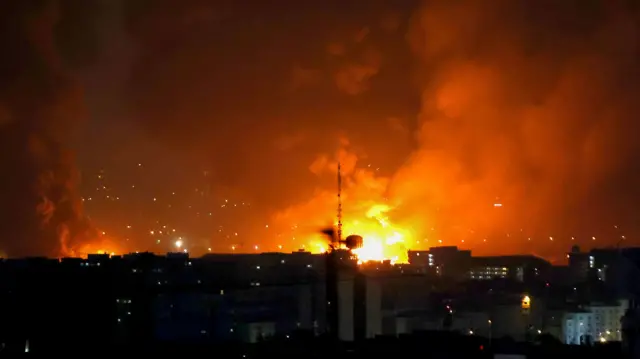 A large orange fire burns in the distance at Mehrabad airport over Tehran's skyline.