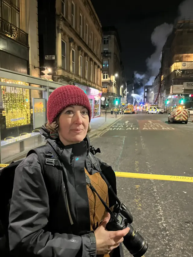 Woman at scene of fire with large camera around her neck