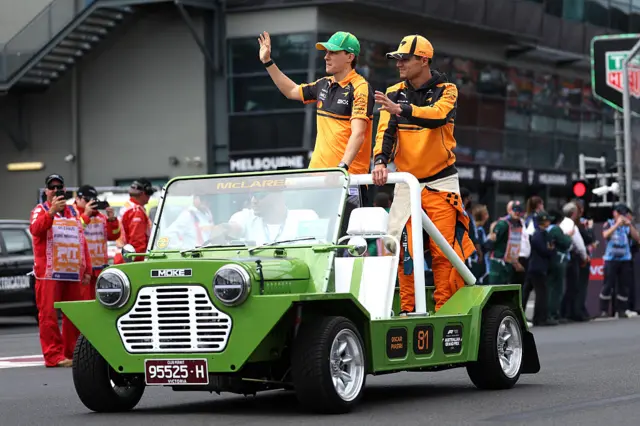 Lando Norris and Oscar Piastri in a green car during the drivers' parade