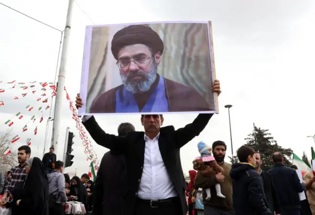 A man holds a picture of Mojtaba Khamenei