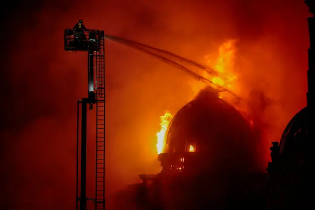A firefighter on a high ladder extinguihsing the fire