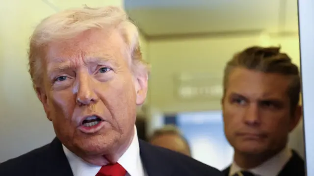 Trump speaks to reporters aboard Air Force One on a flight from Delaware to Florida on 7 March as US Defence Secretary Pete Hegseth watches on from behind him.