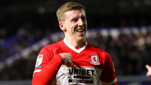 Matt Targett points at his own chest while smiling