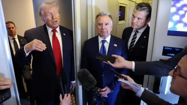 Trump speaking aboard Air Force One as reporters hold up microphones to him