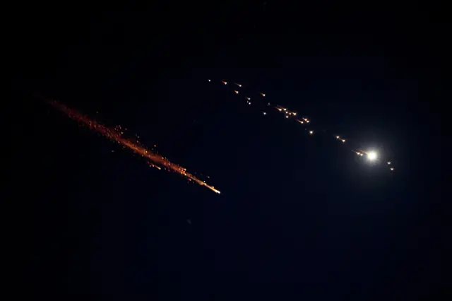 Missile fire is seen in the sky above the Israeli coastal city of Netanya, during a fresh barrage of Iranian strikes overnight