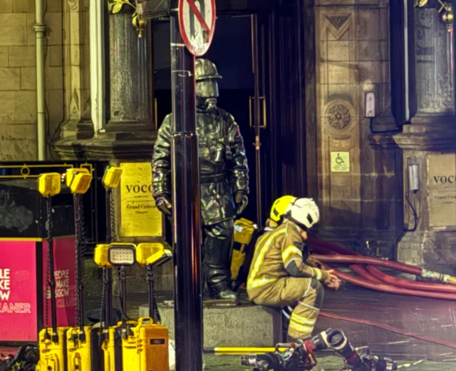 Early this morning two of the firefighters resting below the statue ‘Citizen Firefighter’ - outside Grand Central Hotel. The bronze statue is a tribute to firefighters past and present