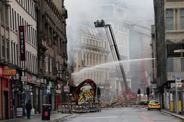 Rubble from the collapsed Victorian sandstone building lies in the street next to the railway station's Union Street entrance as firefighters continue to damp down the smoking structure.