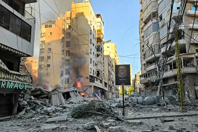A fire burns at the site of a collapsed building surrounded by apartment blocks following an Israeli airstrike on Beirut's southern suburbs
