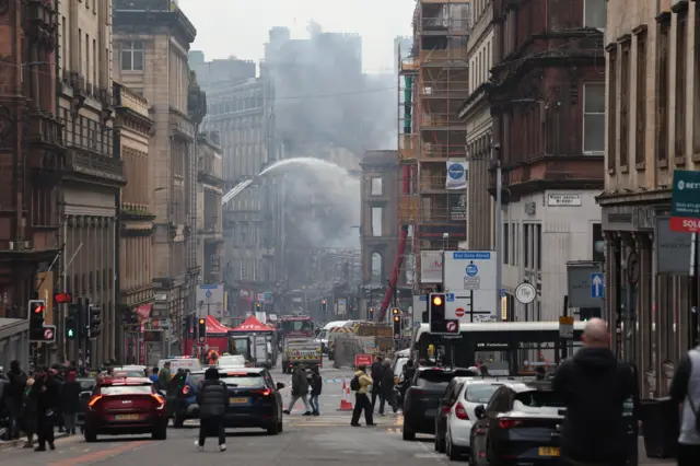 Firefighters damp down the remains of a fire which broke out in a building adjacent to Glasgow Central railway station on Sunday