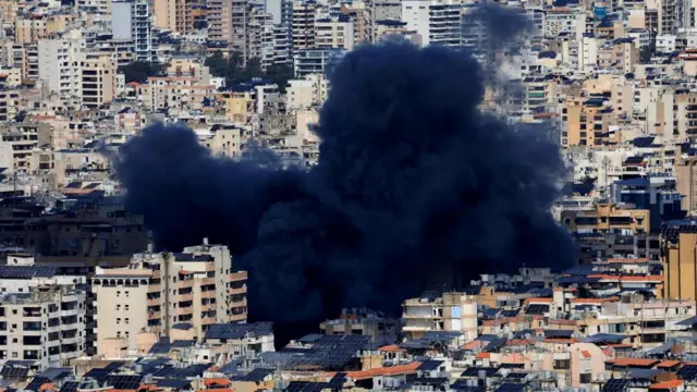 A large thick cloud of black smoke coats tower blocks in Beirut