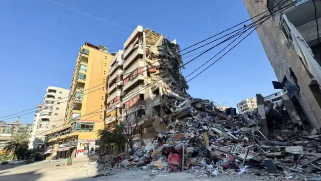 Half of a tower block in Beirut is reduced to rubble and lies next to the remains of the building