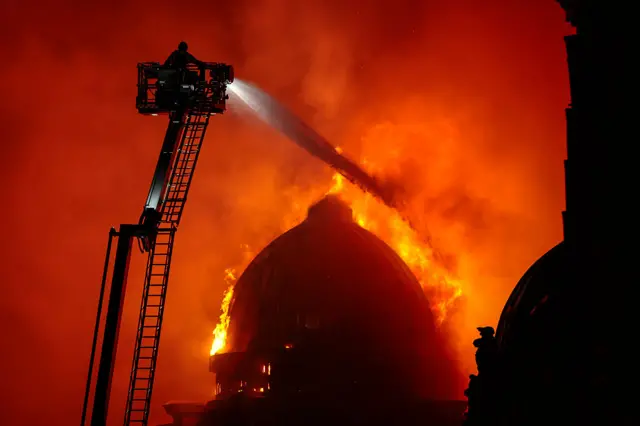 Firefighters on a high ladder blasting water at the dome