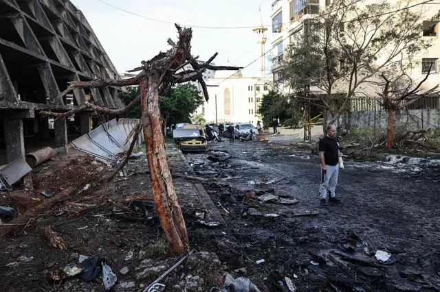 A man walks among the debris on a street of Beirut in Lebanon, a heavily damaged building to the left of the frame