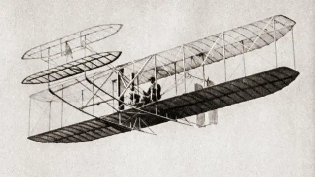 A grey image of the Wright Flyer in the air